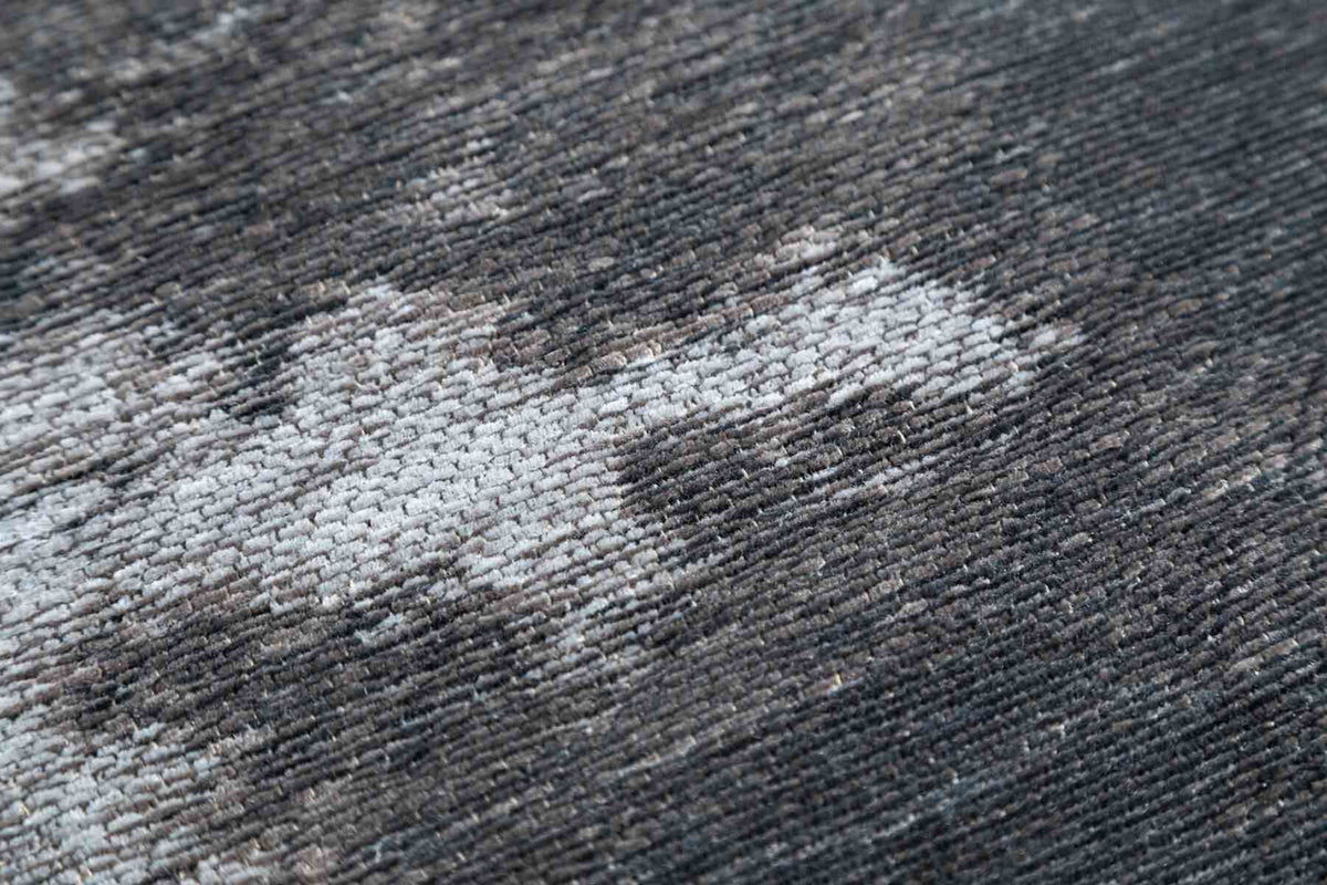 Szary dywan Carrara z kolekcji Macieja Zienia o strukturze miękkich nici szenilowych z wzorem inspirowanym kamieniem.